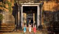 A troupe of Apsara dancers enter the eastern entrance of Banteay Samre temple as the sun fades for the day
