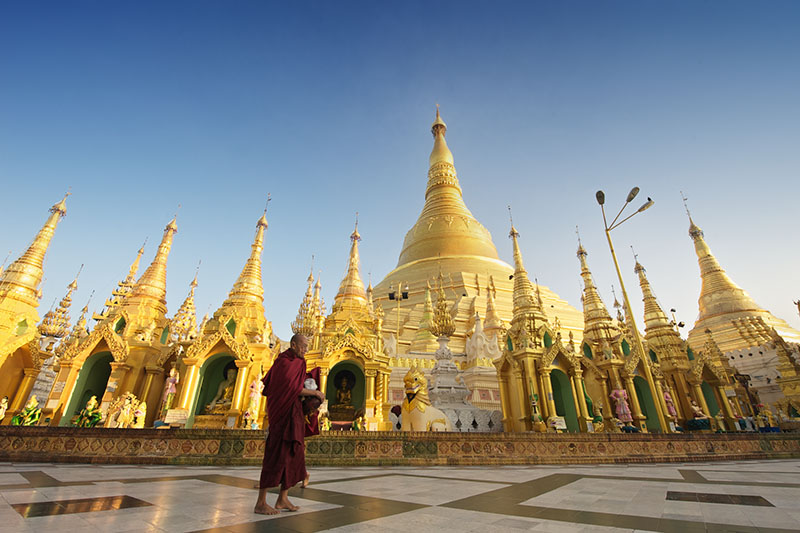 A lone monk circumnavigates the grounds of revered Shwedagon Pagoda in the late afternoon light